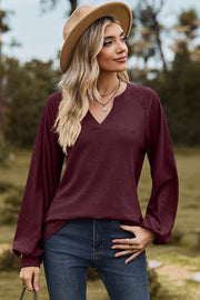 Burgundy waffle knit raglan v-neck top with textured sleeves.