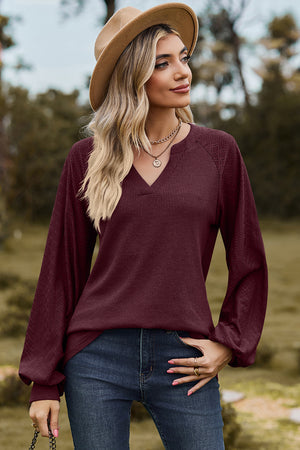 Burgundy waffle knit raglan v-neck top with textured sleeves.