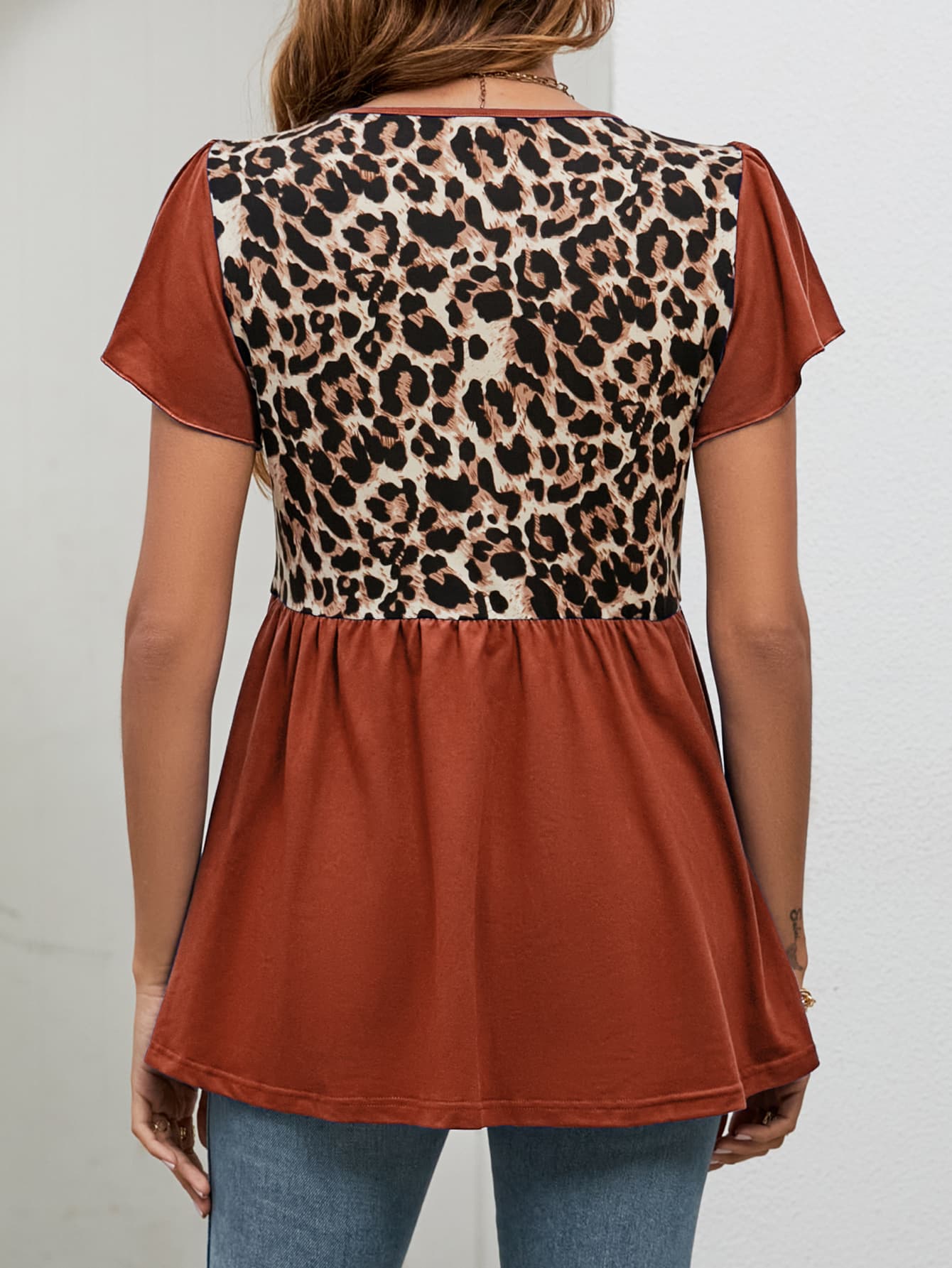 Leopard panel peplum top in rust with short flutter sleeves and a ruffled hem.