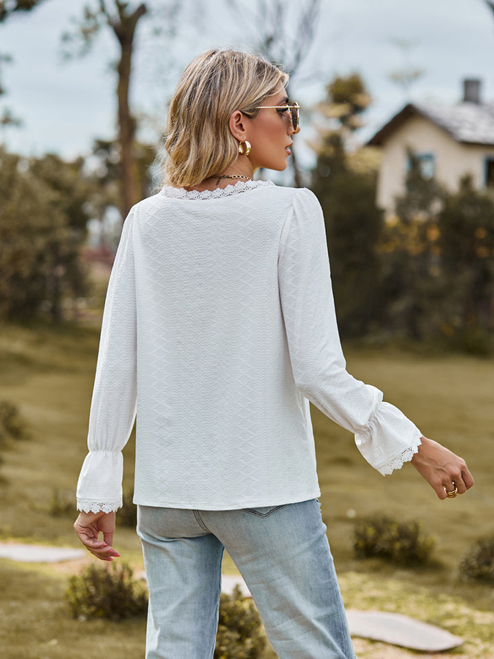 White lace trim textured blouse with ruffled cuffs and neckline.