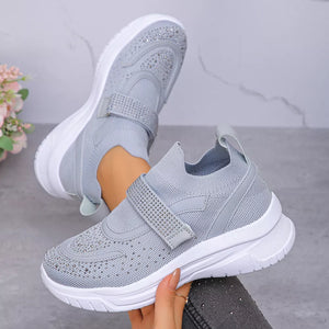 Gray mesh slip-on sneakers with adjustable rhinestone strap and white sole.