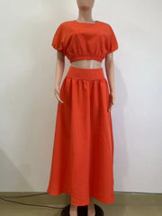 Orange crop top with puff sleeves and elastic hem, paired with a high-waisted maxi skirt.