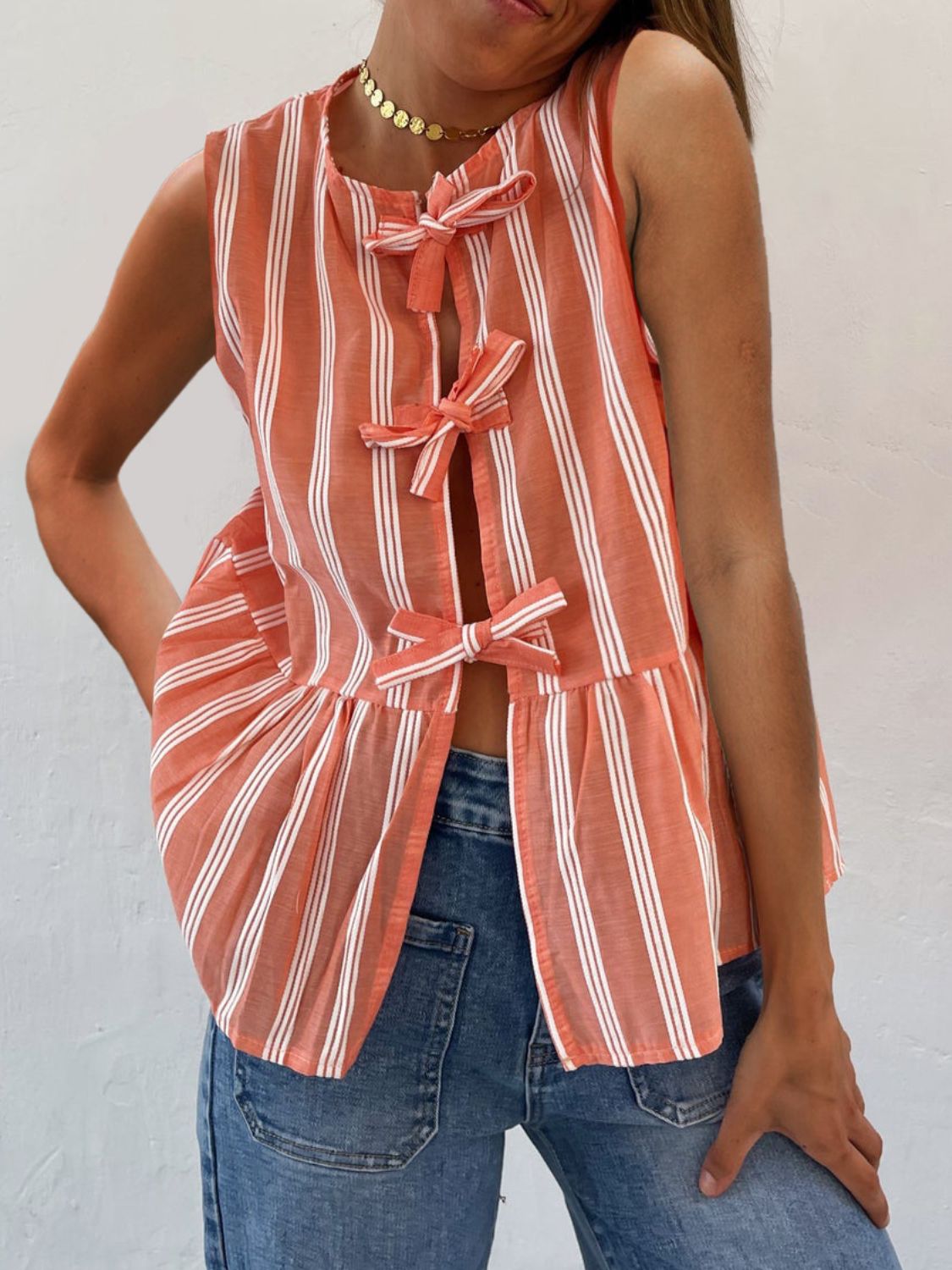 Orange and white striped peplum top with bow tie closures and a ruffled hem.