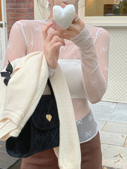 Sheer mesh shirt with all-over white bow print, long sleeves, and mock neck.