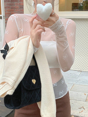 Sheer mesh shirt with all-over white bow print, long sleeves, and mock neck.