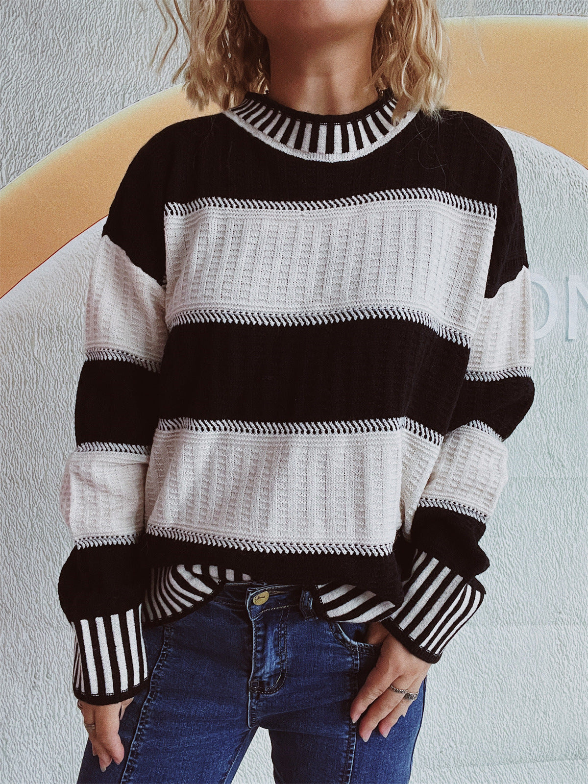 Black and white striped mock neck sweater with textured knit panels and ribbed cuffs.