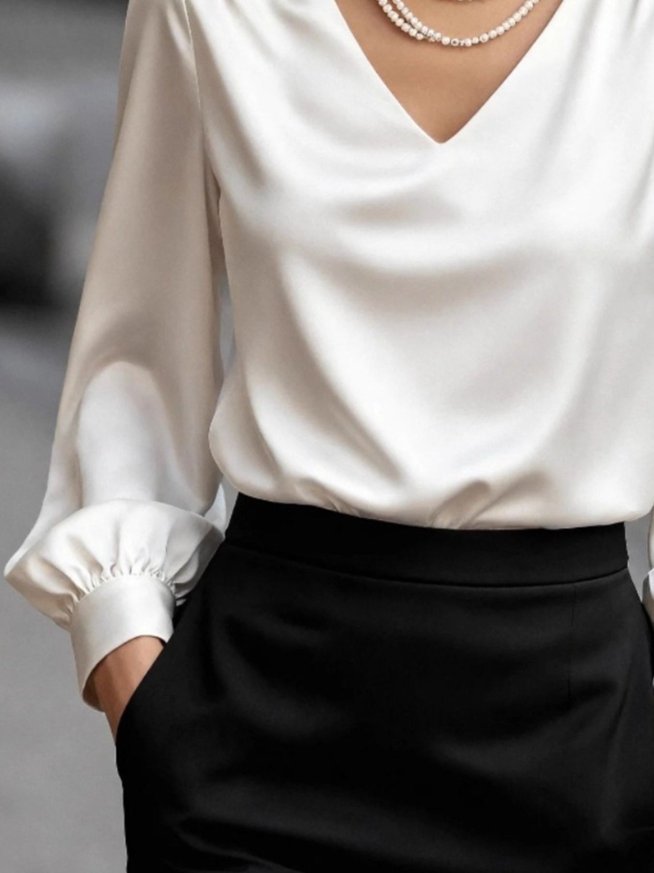 White satin V-neck blouse with long sleeves and gathered cuffs.