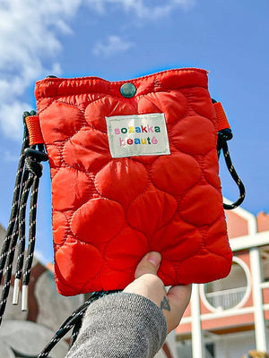 Red quilted mini crossbody bag with circular pattern and adjustable strap.