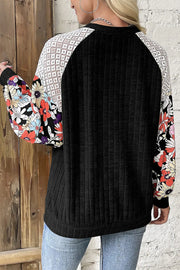 Black blouse with floral print sleeves and lace yoke detail.