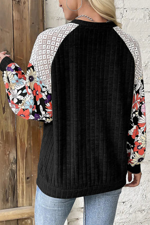 Black blouse with floral print sleeves and lace yoke detail.