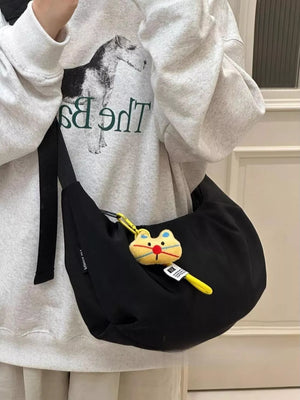 Black crescent shape crossbody bag with cute cat charm and adjustable strap.