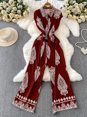Wine red wide leg romper with white paisley print, collared, button-down front, and wide leg pants.
