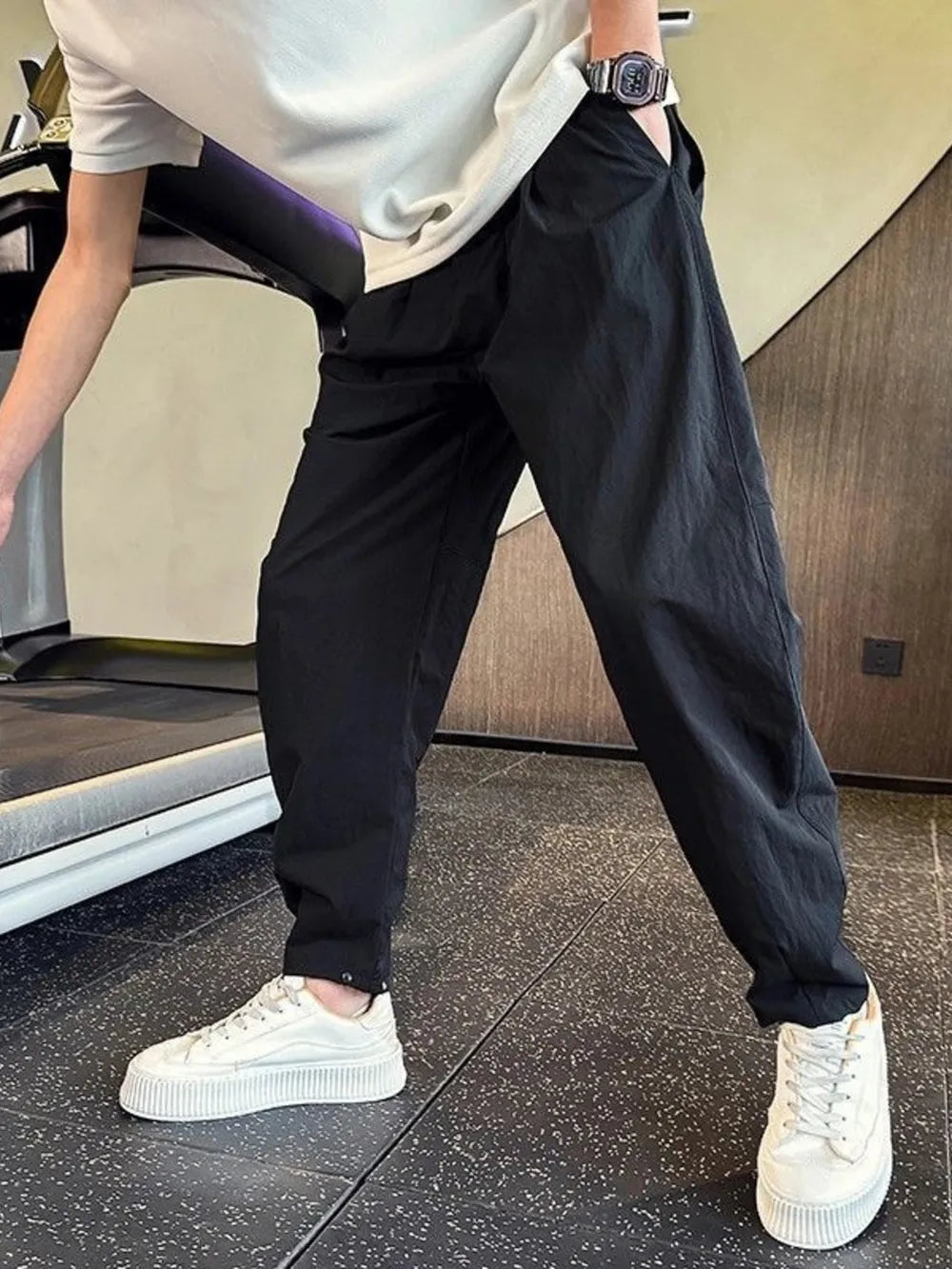 Black cargo pants with adjustable cuffs and a relaxed fit, styled with a white t-shirt and sneakers.