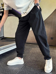 Black cargo pants with adjustable cuffs and a relaxed fit, styled with a white t-shirt and sneakers.