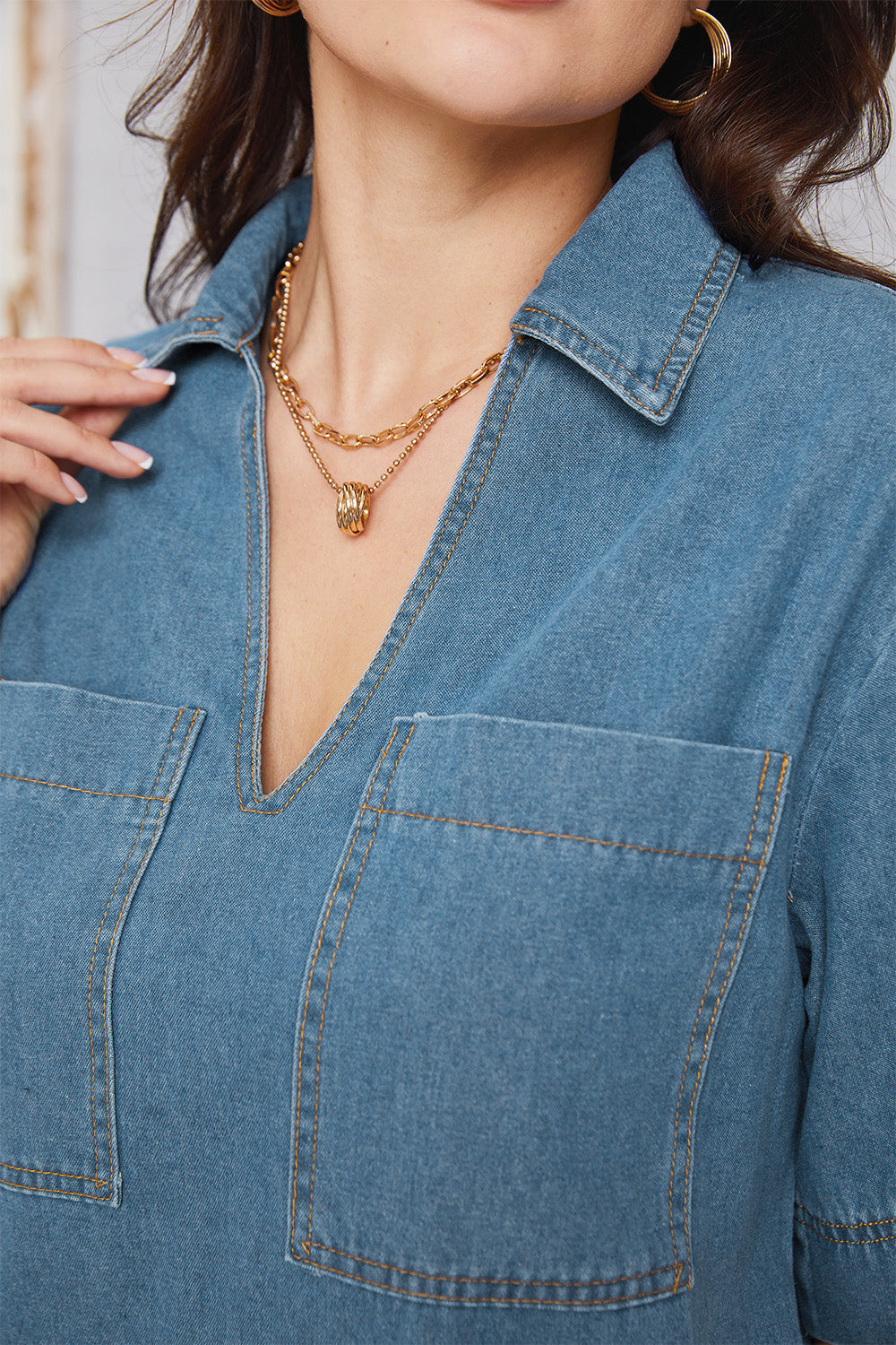 Denim mini dress in medium wash with plunging collar and chest pockets.