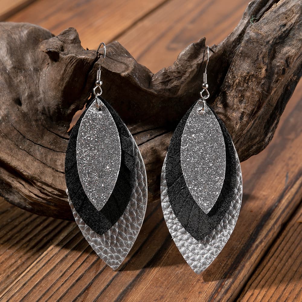 Layered faux leather statement earrings in silver, black, and textured silver.