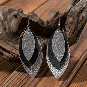 Layered faux leather statement earrings in silver, black, and textured silver.