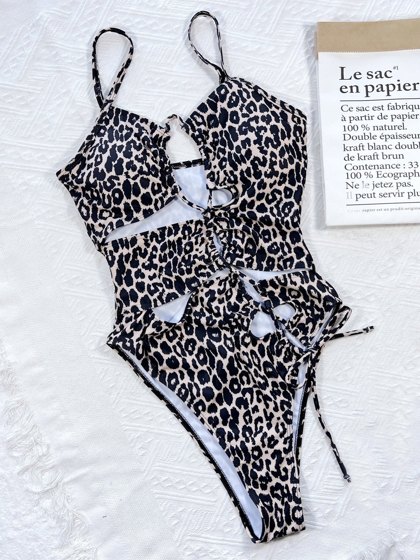 Leopard print one-piece swimsuit with cutout details and lace-up front.