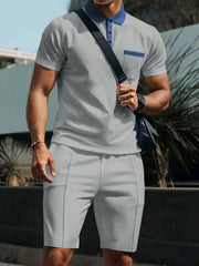 Grey polo shirt and shorts set with blue accents, textured fabric, short sleeves, and a chest pocket.