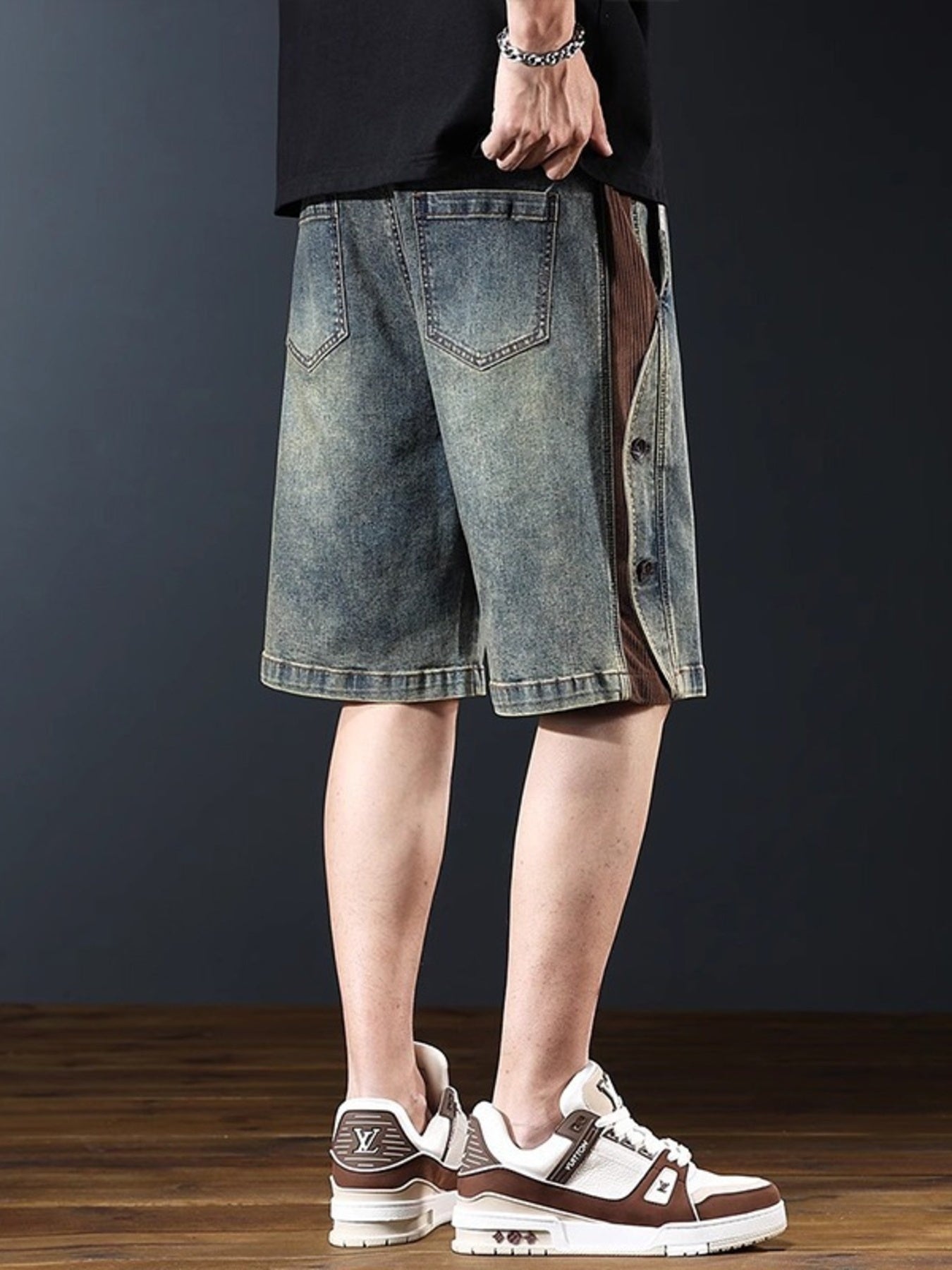 Men's wide leg denim shorts in medium wash with brown corduroy side panel and button detail.
