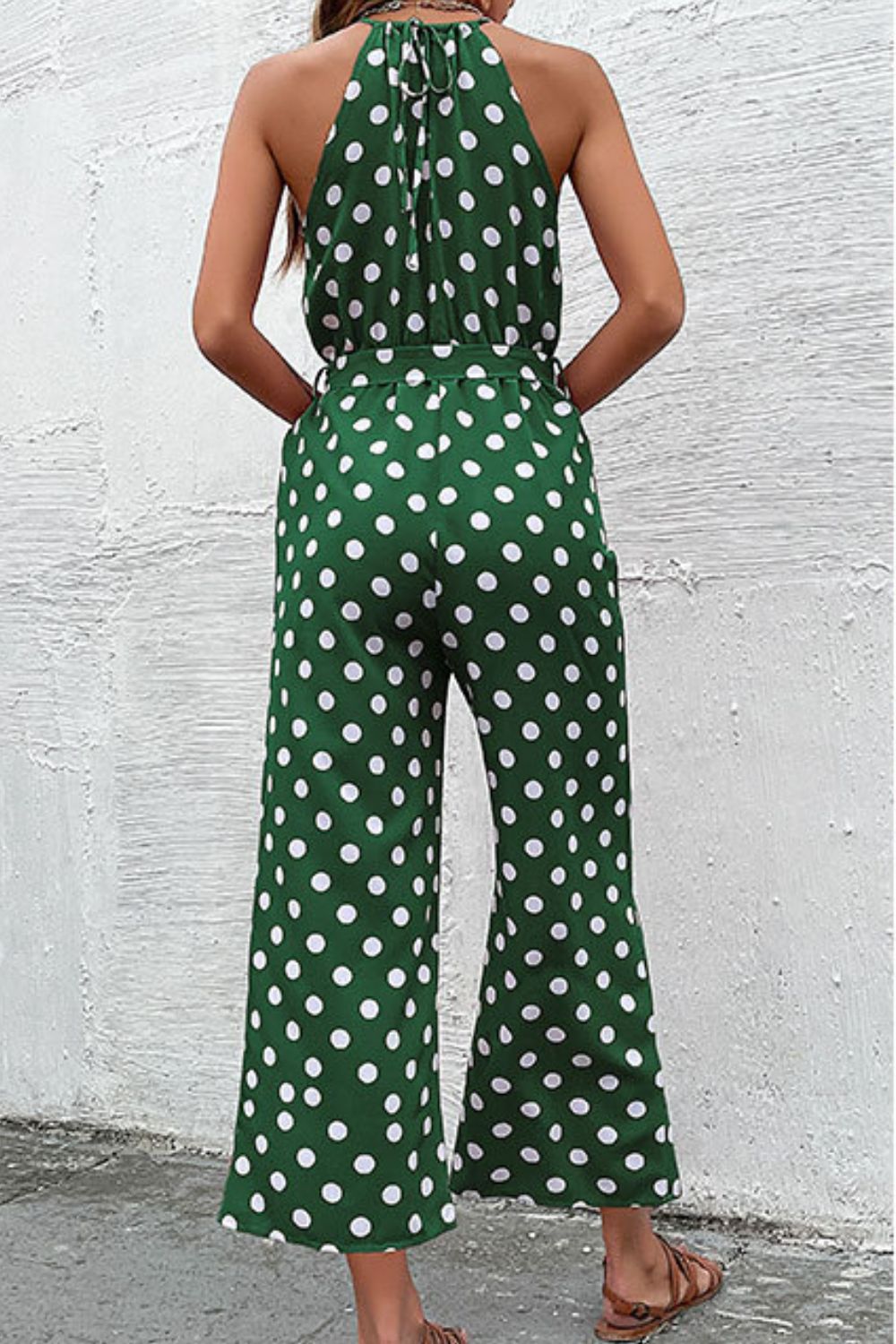 Green polka dot halter neck palazzo jumpsuit with tie back and belted waist.