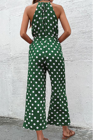 Green polka dot halter neck palazzo jumpsuit with tie back and belted waist.