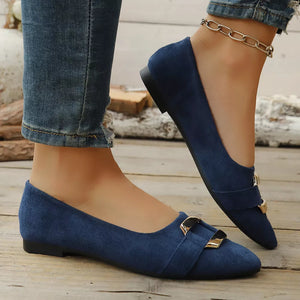 Navy blue slip-on flats with pointed toes and gold buckle detail.