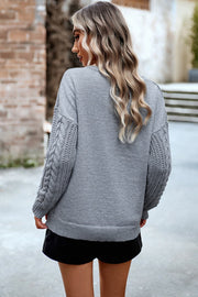 Light gray acrylic sweater with cable-knit sleeves and relaxed fit.