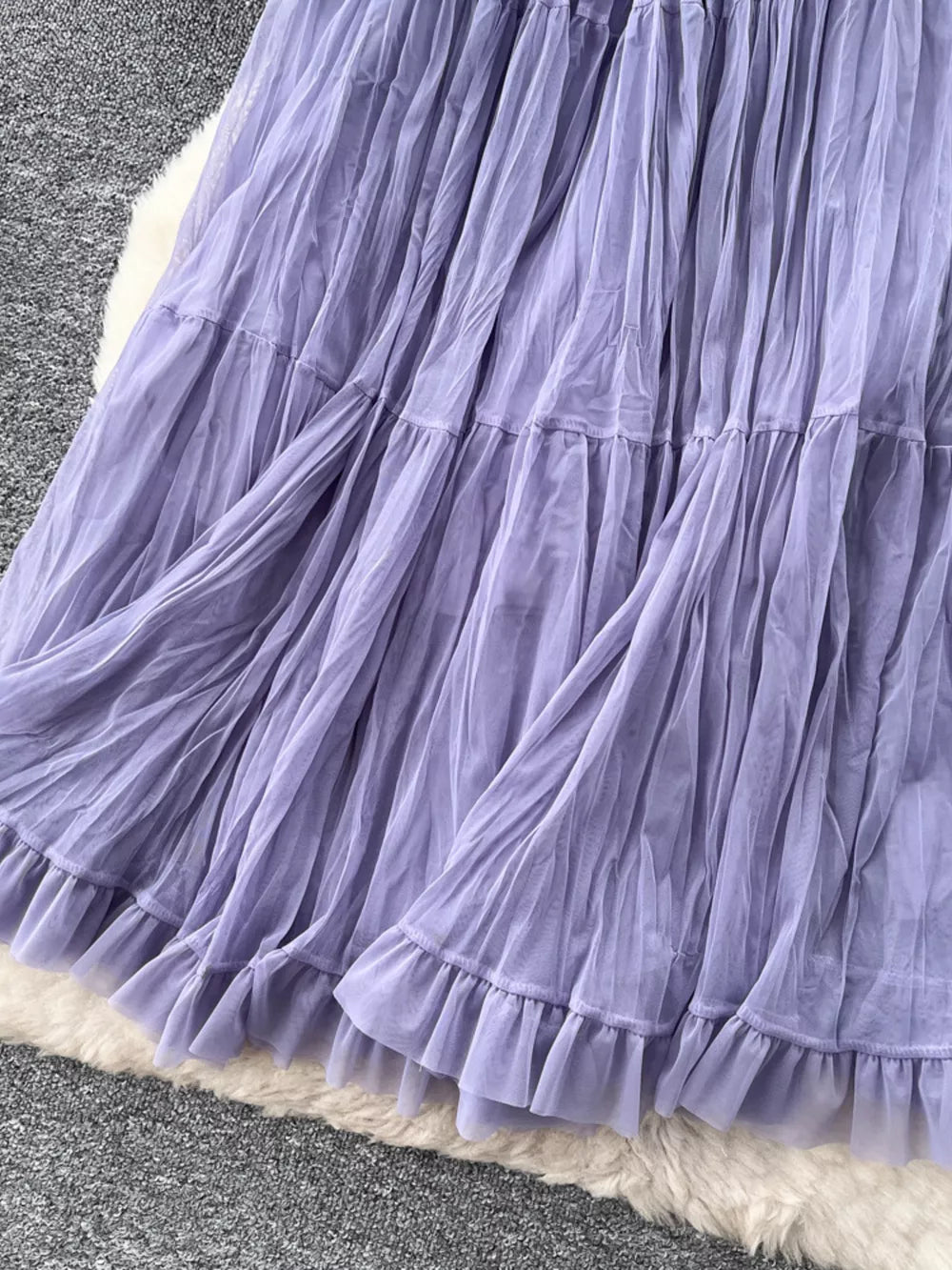 Purple tiered tulle skirt with ruffled hem and lining, showing fabric texture.
