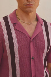 Striped knit polo shirt in red-violet with button front and spread collar.