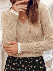 Pearl-adorned beige V-neck knit sweater with lace cuffs and open knit details.