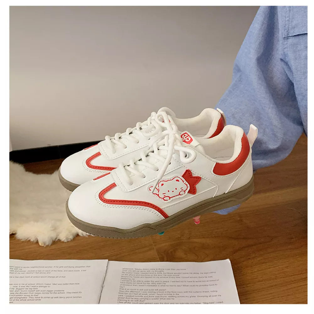 White lace-up sneakers with red trim and a cartoon cat accent.
