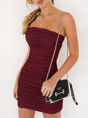 Burgundy ruched strapless bodycon mini dress with a chain strap bag.