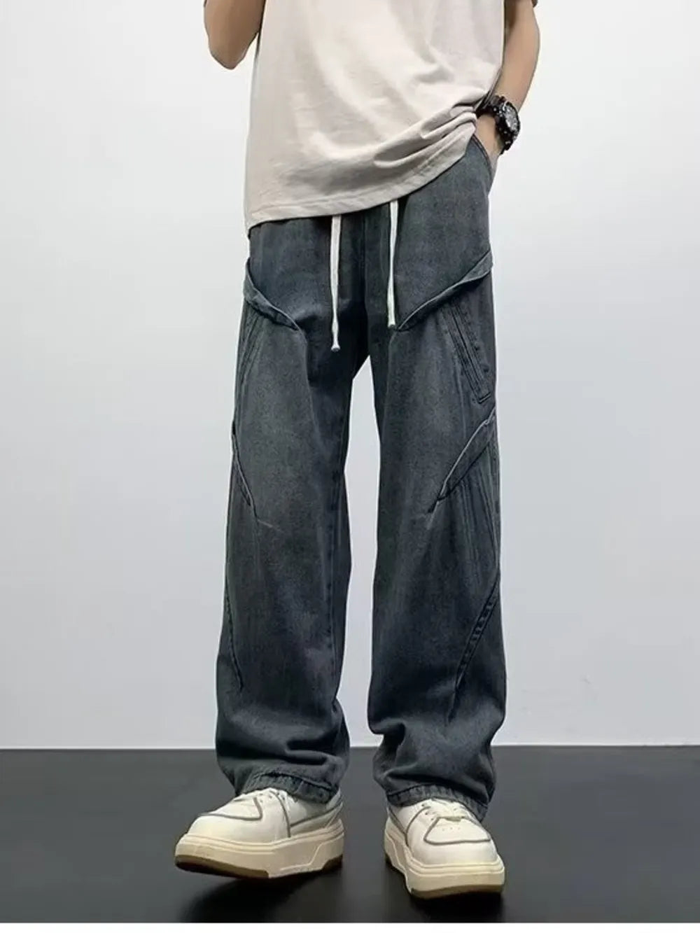Gray oversized drawstring jeans with contemporary paneling and a relaxed fit.
