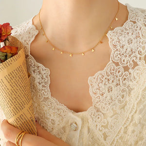 Gold dangling charm chain necklace with small triangle charms.