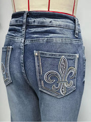 Classic high-waisted flare jeans in blue denim with ornate embroidered fleur-de-lis back pockets.