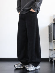 Men's black wide-leg sweatpants with pockets, relaxed fit, and textured fabric.