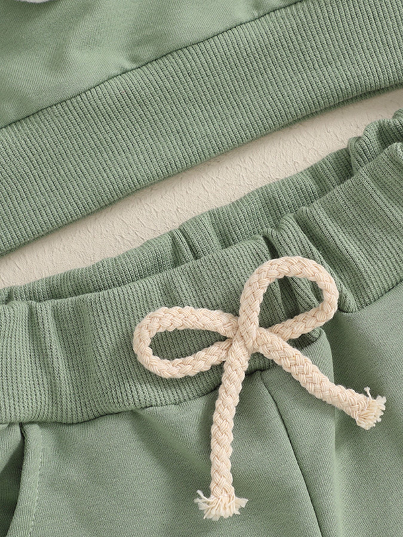 Green cotton baby outfit set with ribbed waistband and drawstring detail.