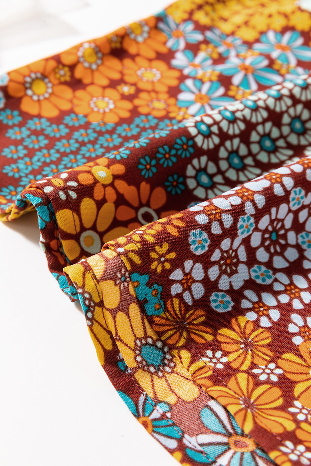 Floral patchwork culotte jumpsuit in brown with yellow, orange, and blue flowers.