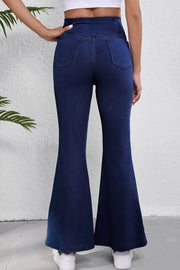 Crossover waist denim flare trousers in medium wash, showing back pockets and flared leg opening.