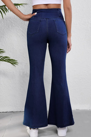 Crossover waist denim flare trousers in medium wash, showing back pockets and flared leg opening.