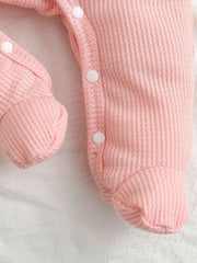 Blush pink waffle knit baby one-piece with white snap buttons and footies