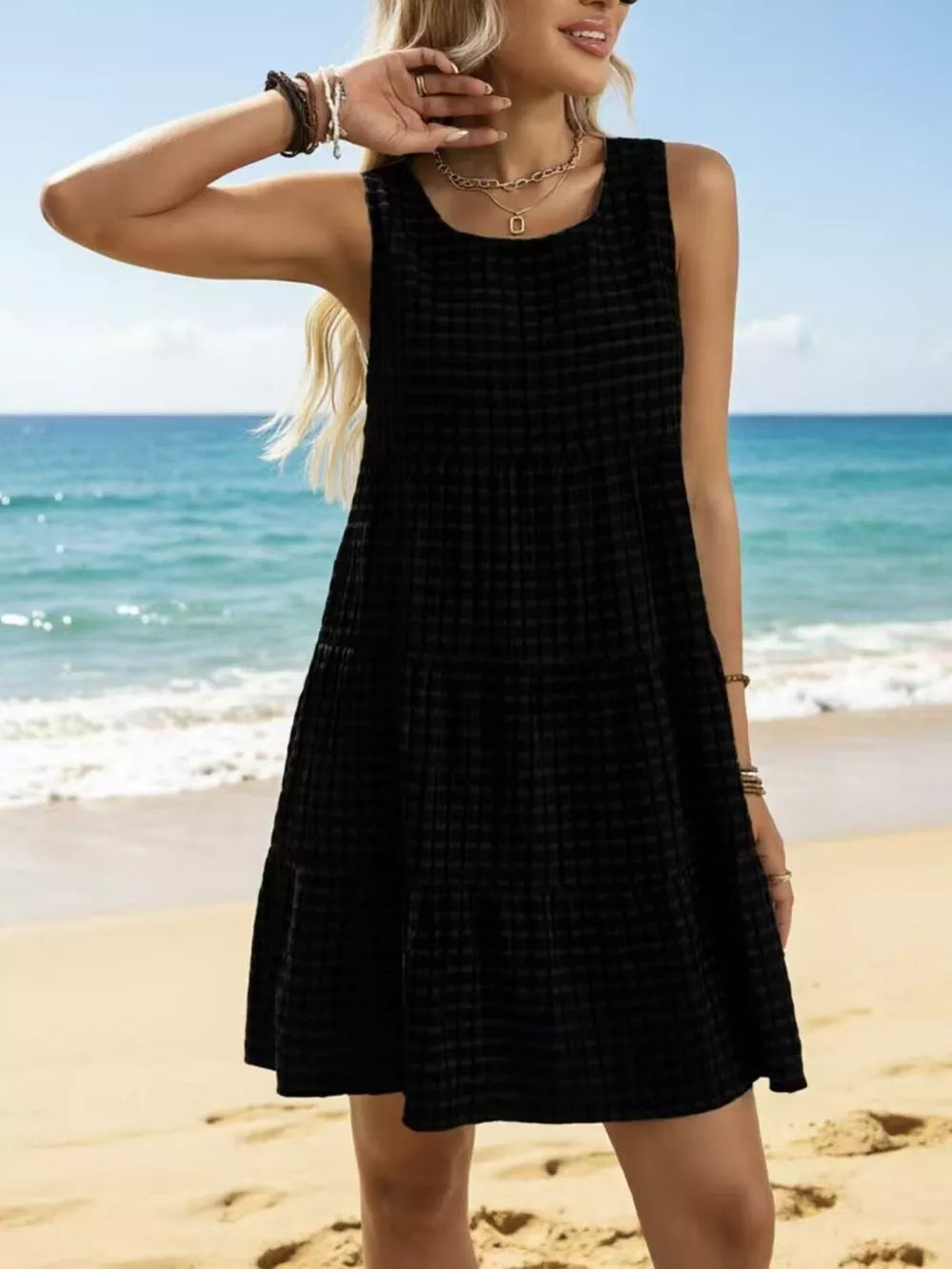 Black tiered mini dress with textured pattern, round neck, sleeveless, above knee length