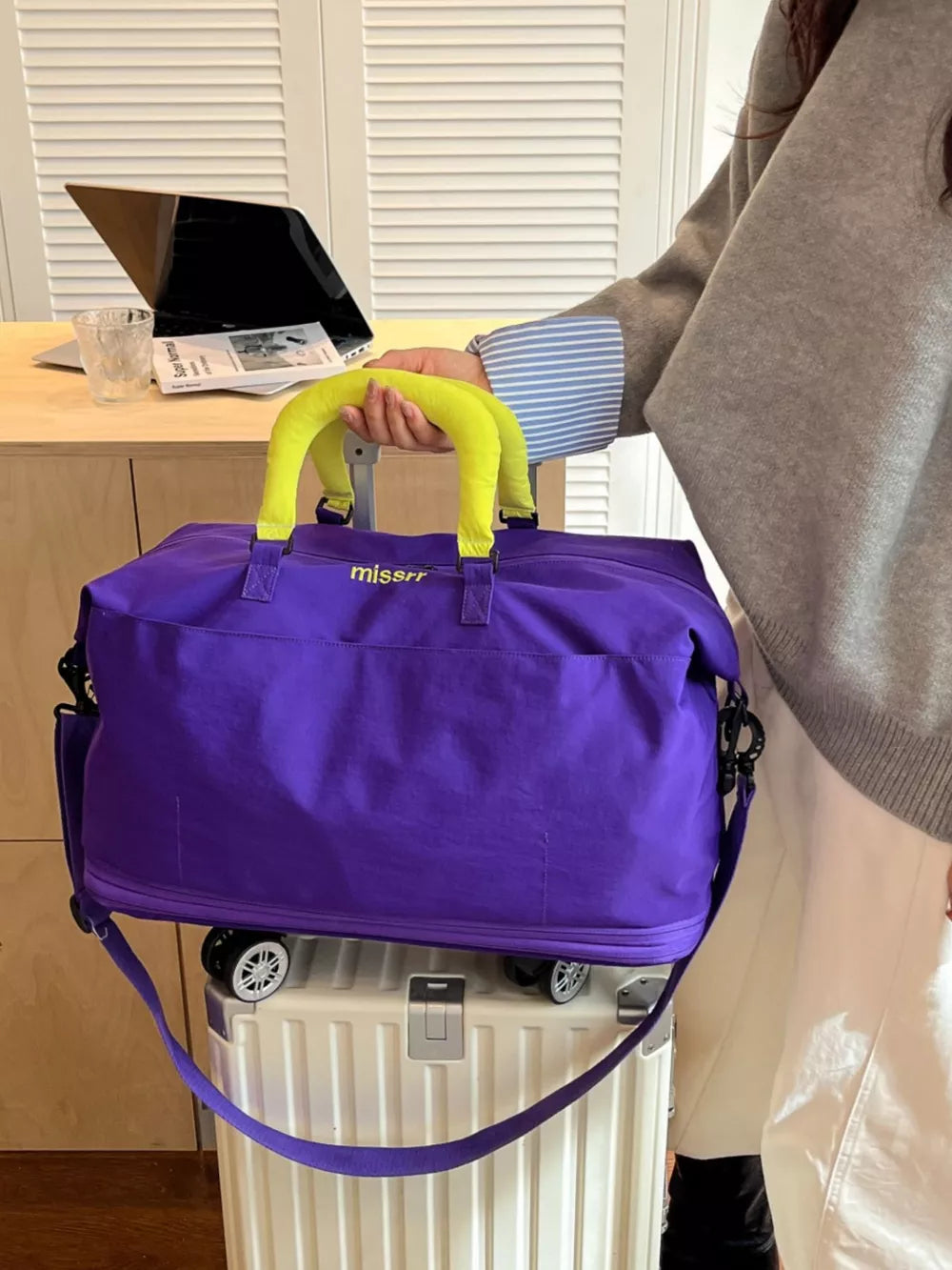 Vibrant purple travel bag with neon yellow handles and a crossbody strap.