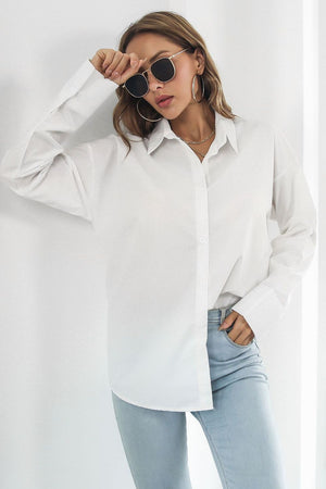 Oversized white cotton poplin shirt with button front and long sleeves styled with jeans.