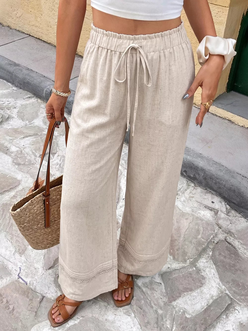 Beige wide-leg maternity trousers with drawstring waist and lace trim detail.