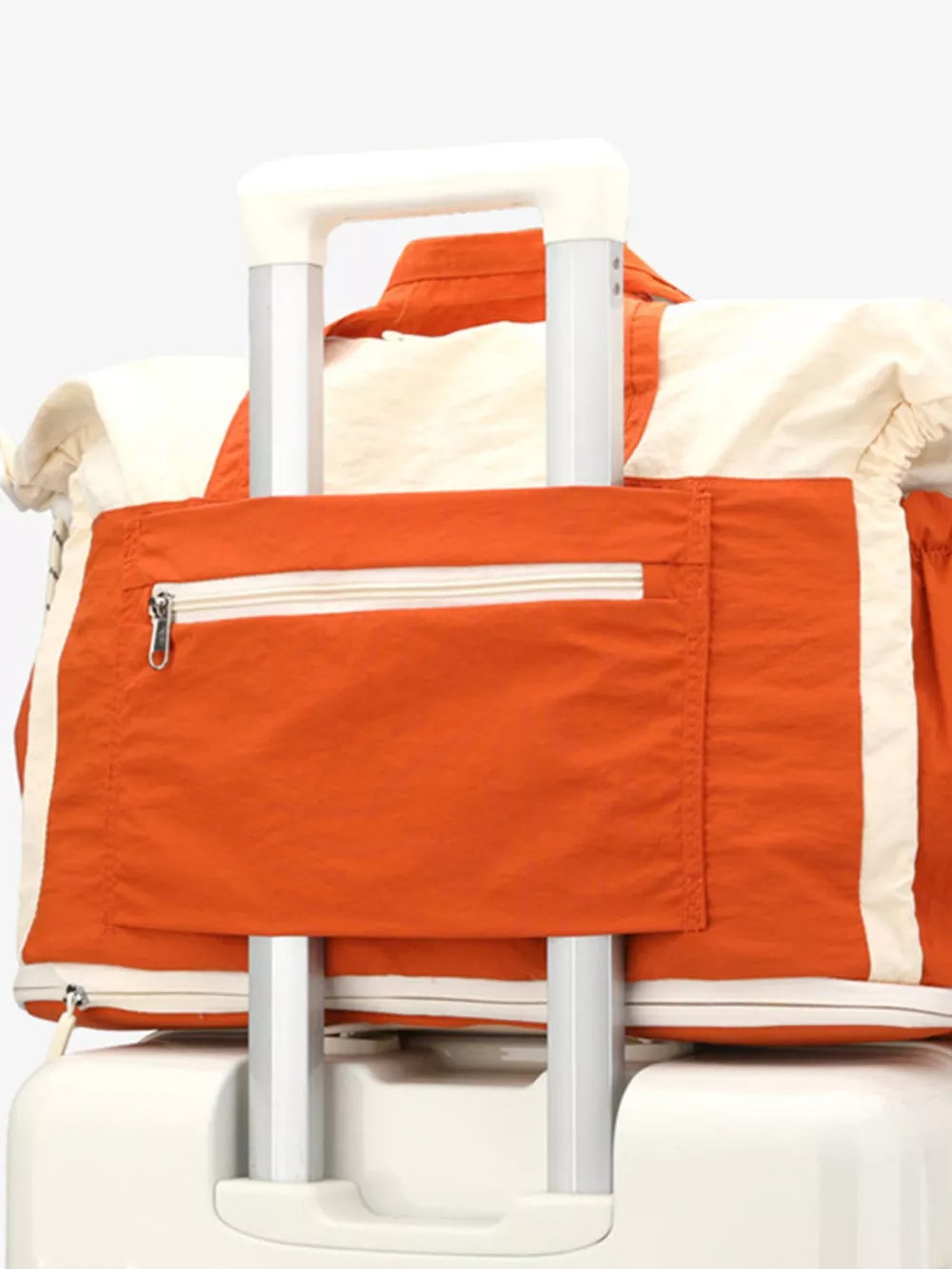 Color-block travel bag with orange front pocket and white trim, attached to luggage handle.
