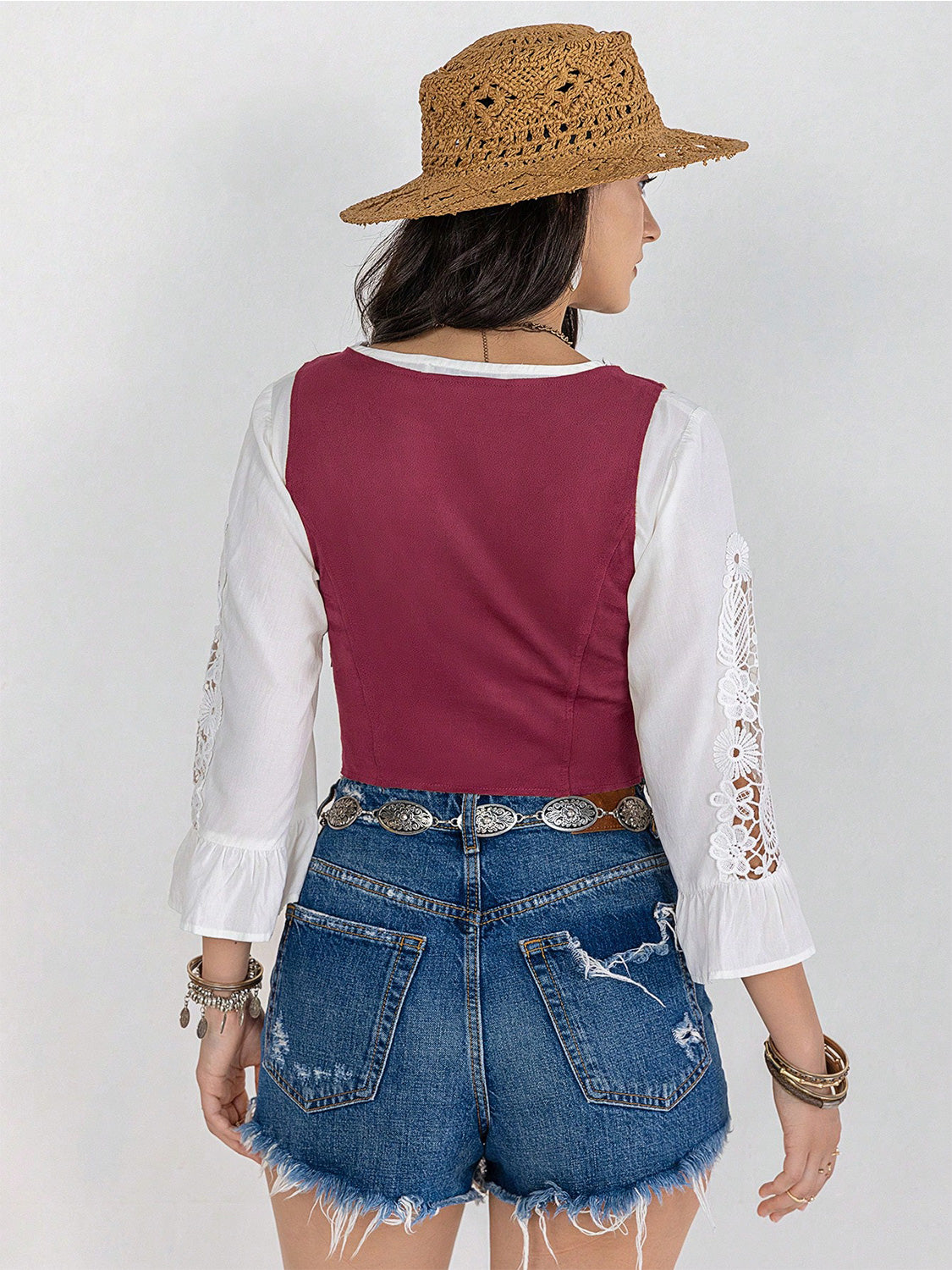 Cerise lace-up corset vest with white bell sleeves and lace detail, styled with denim shorts.
