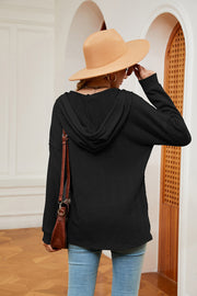 Black textured henley hoodie with drop shoulder and long sleeves.