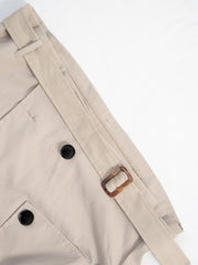 Beige cropped double-breasted trench coat with belt and tortoise buckle detail.